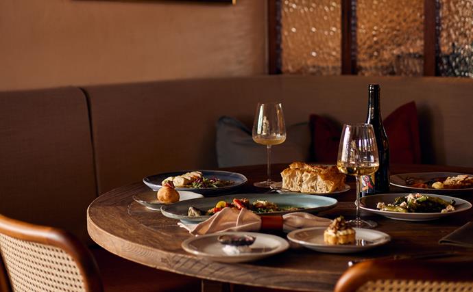 How the Gourmet Traveller Restaurant Guide works image of timber table with snacks and wine glasses