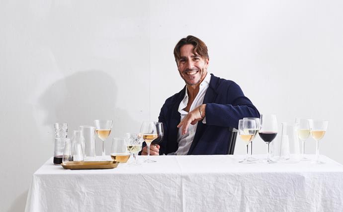 Portrait of Ned Goodwin with glasses of white and red wine on a white tablecloth-covered table
