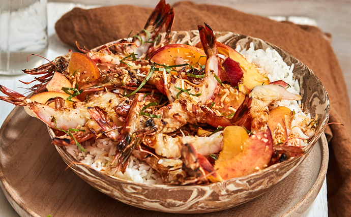 A brass bowl of grilled prawns with coconut rice and peach sambal