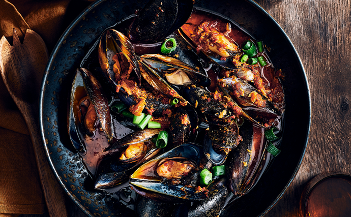 XO mussels stir-fried in XO sauce  in a dark ceramic bowl